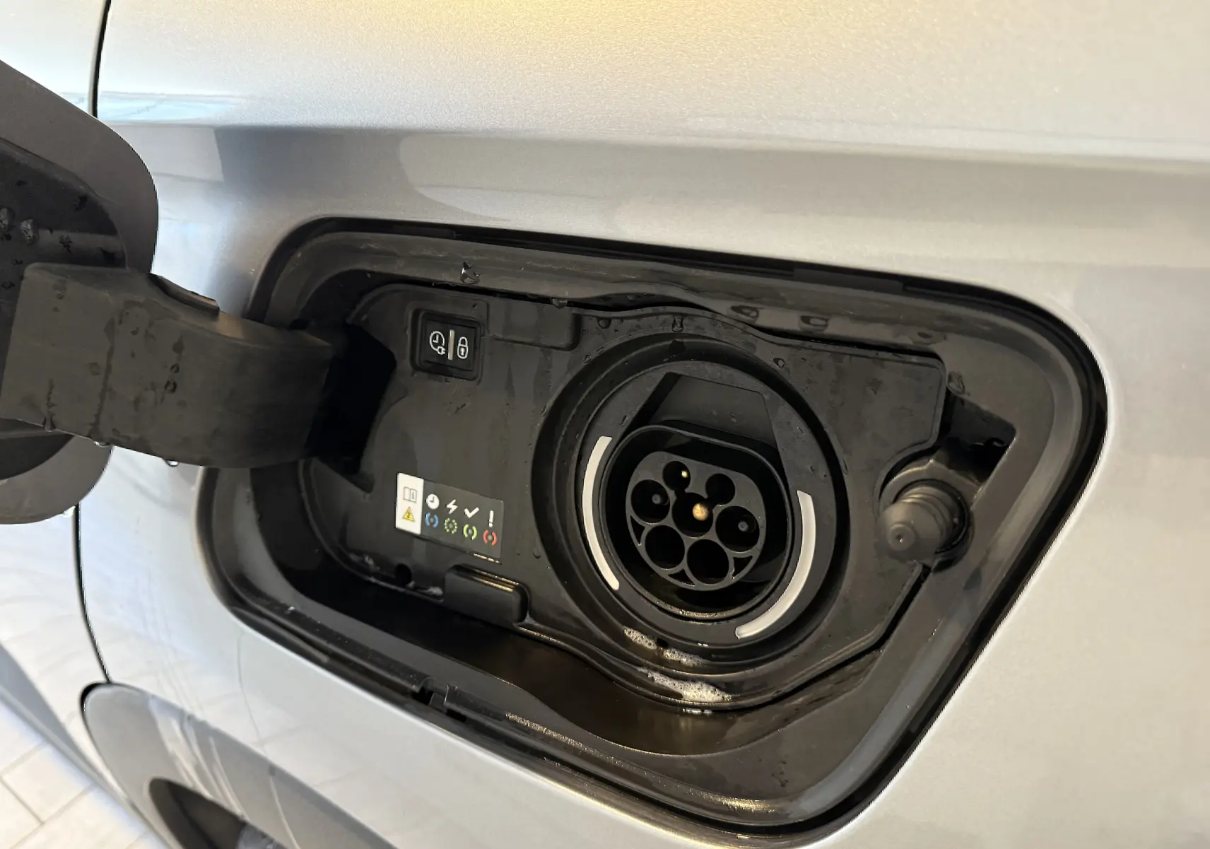 Prise de recharge ouverte côté gauche d'un Opel Grandland X gris Himalaya hybride rechargeable, montrant le connecteur de charge.