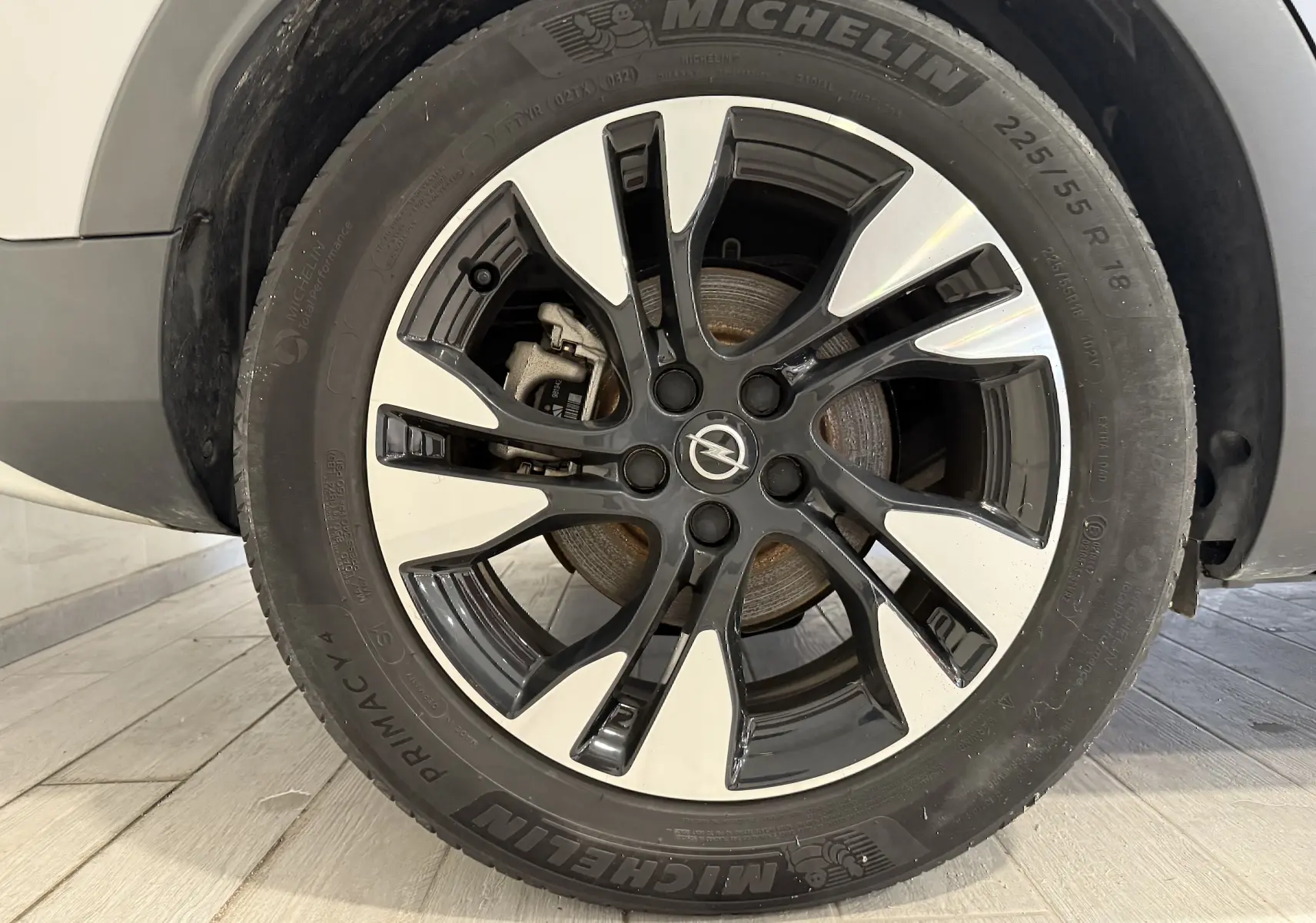 Gros plan sur la jante alliage bicolore noire et argent de l'Opel Grandland X gris Himalaya, avec logo Opel central.