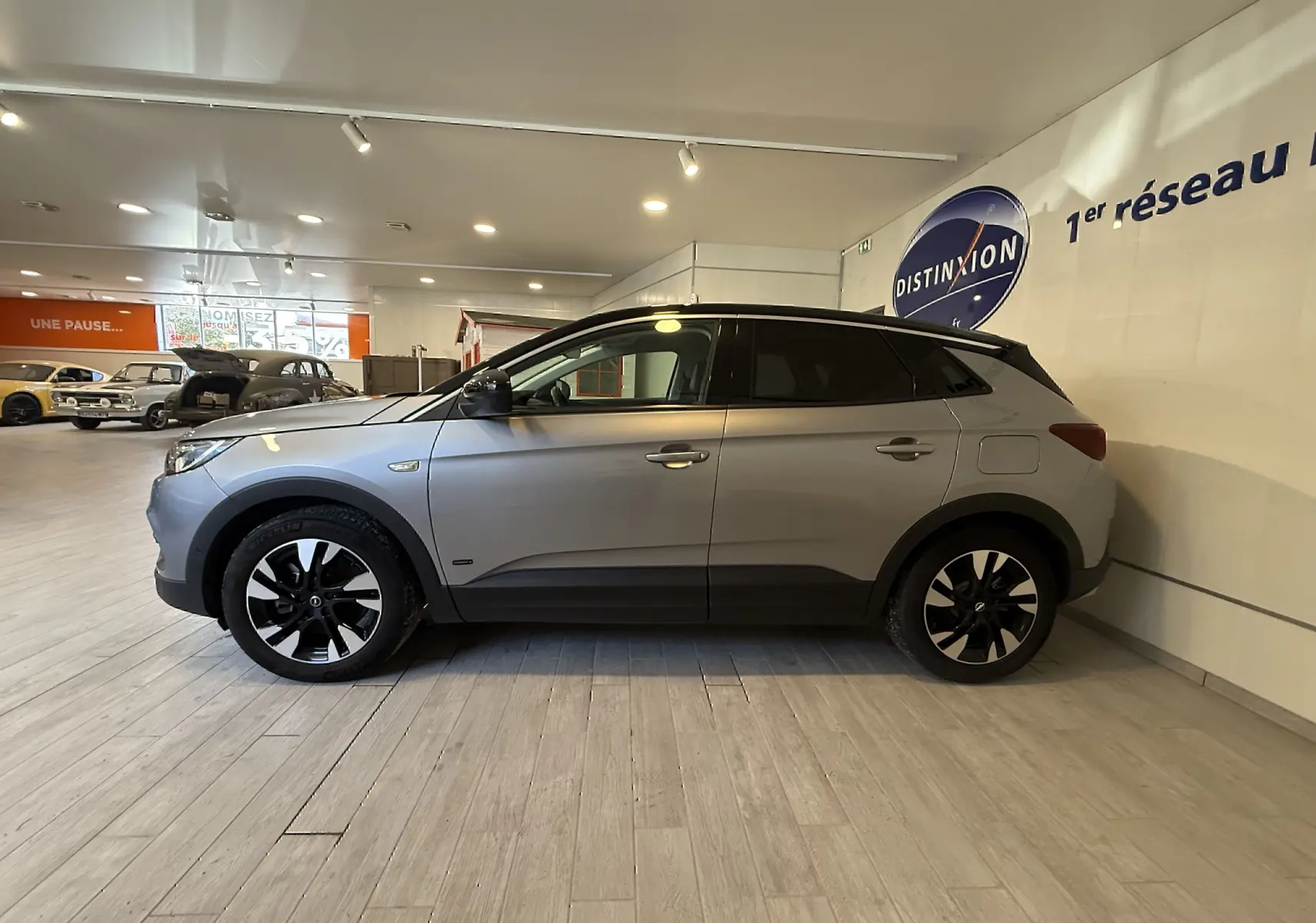 Opel Grandland X gris Himalaya en profil côté gauche, avec jantes noires et toit noir en showroom.