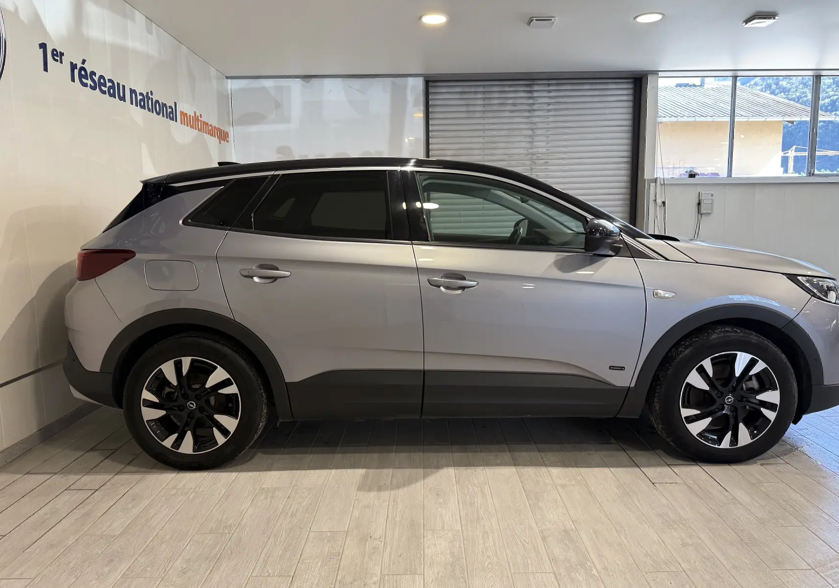 Vue de profil côté gauche d'un Opel Grandland X gris Himalaya métal avec jantes alliage noires et toit noir.