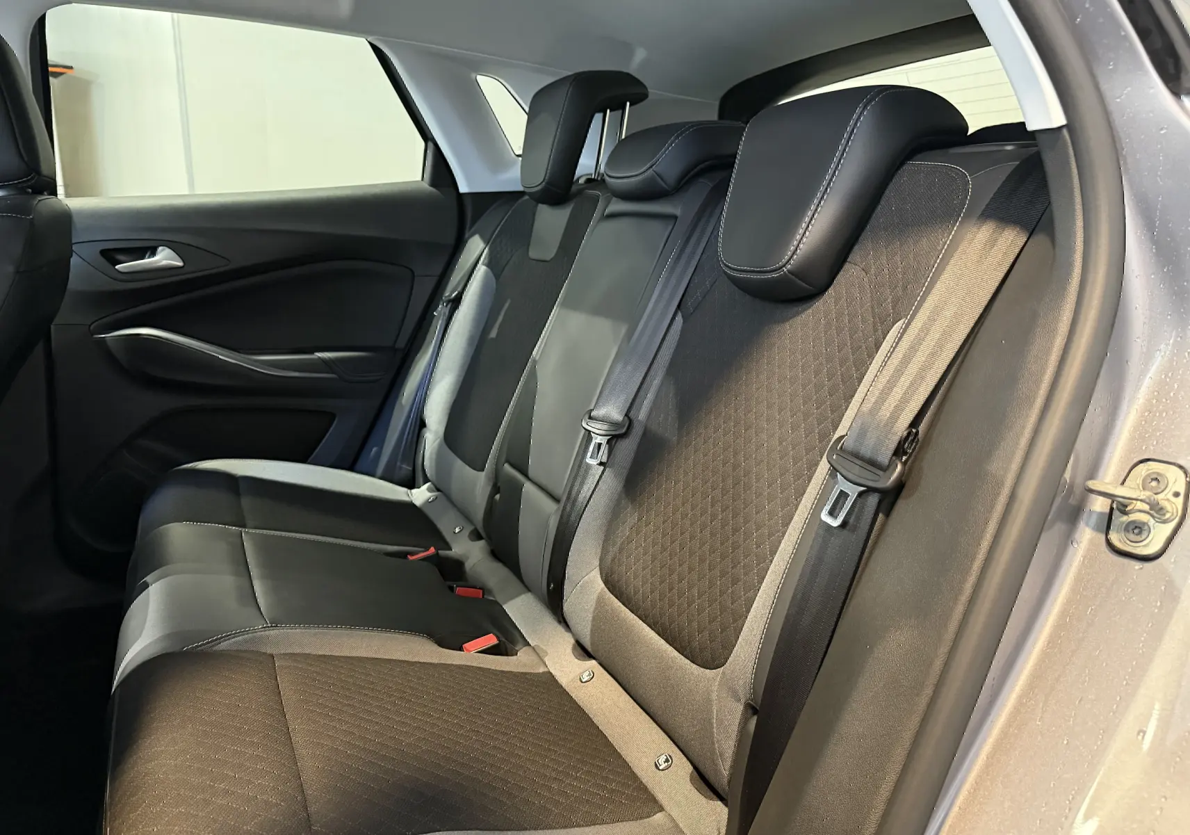 Vue latérale droite de l'intérieur arrière de l'Opel Grandland X gris Himalaya, montrant les sièges en tissu et cuir noir.