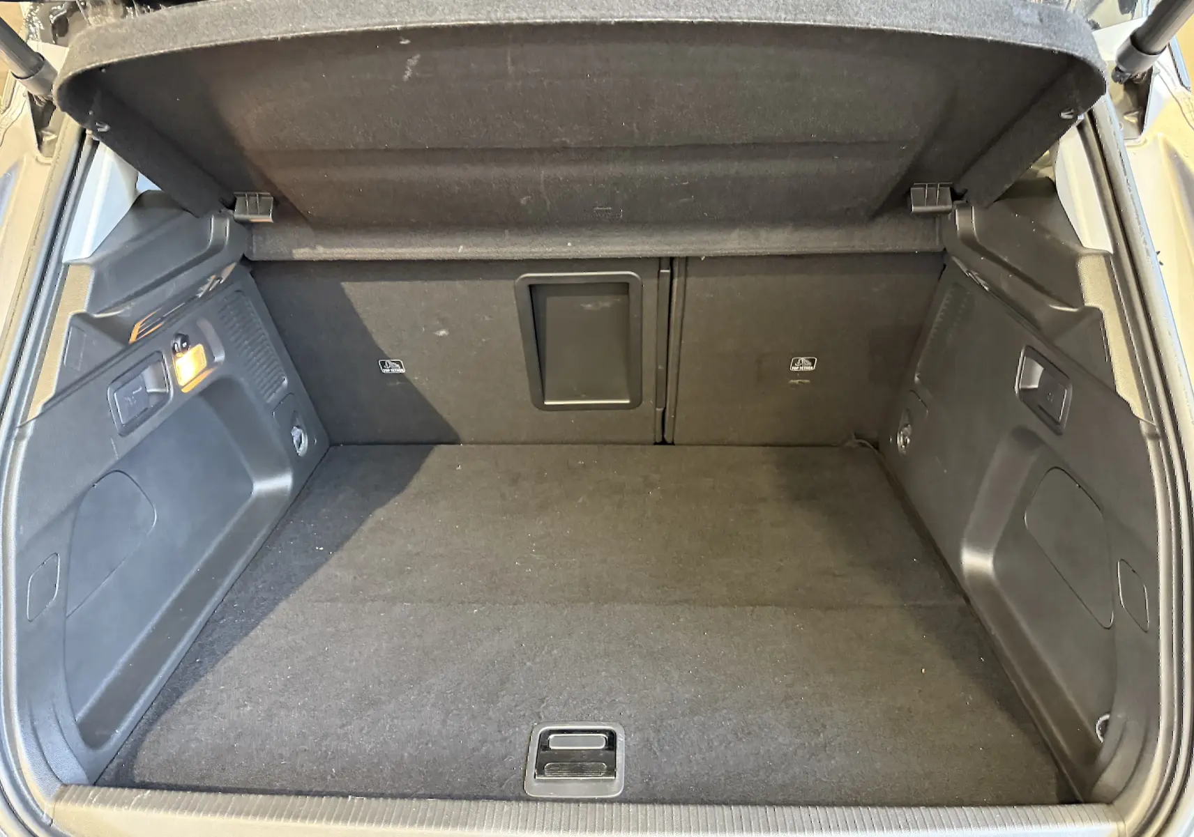 Coffre ouvert d'un Opel Grandland X gris Himalaya, montrant un espace de chargement propre et bien agencé.