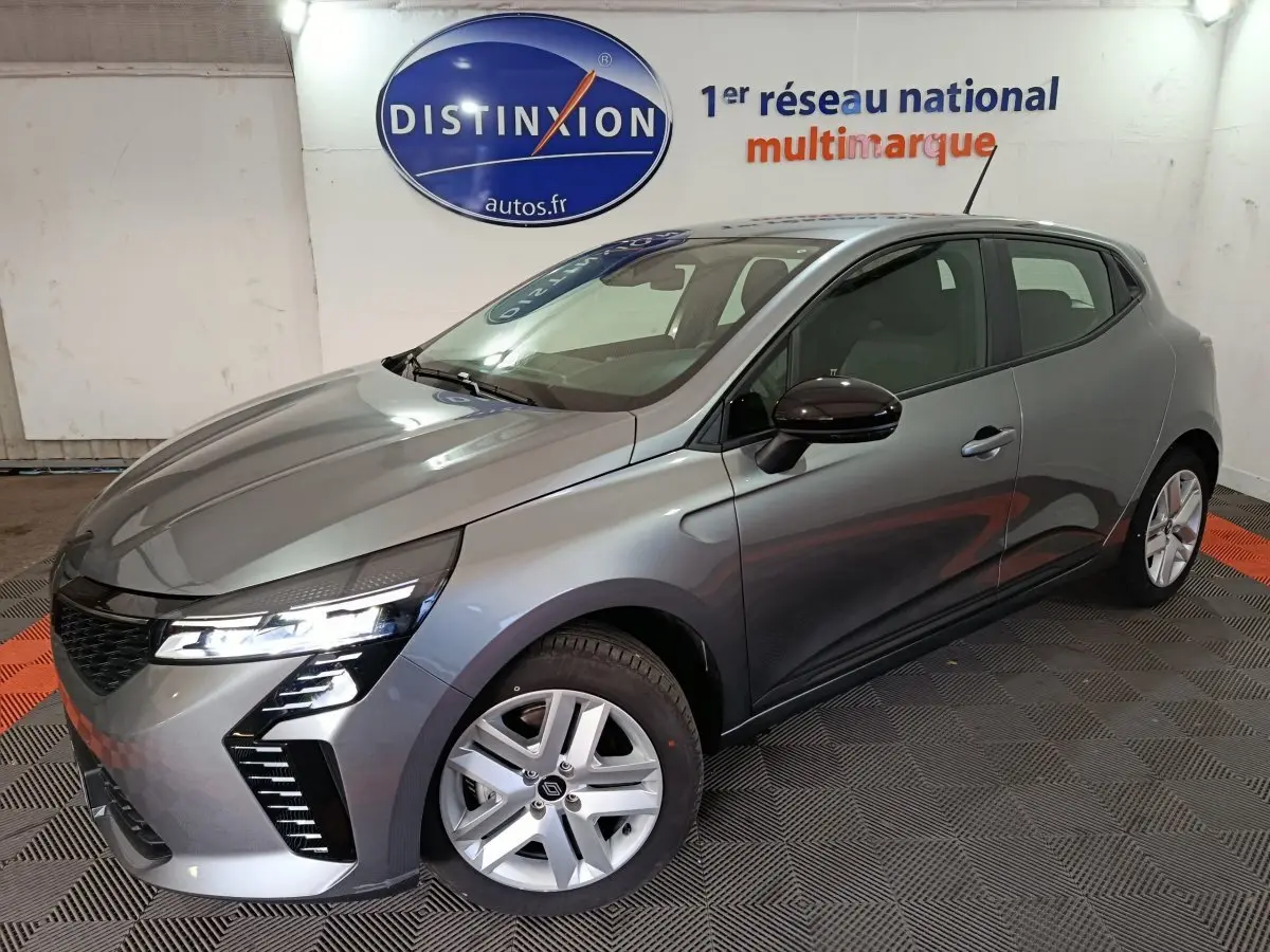 Renault Clio Evolution Blue dCi 100 gris clair vue 3/4 avant droit avec phares LED allumés en intérieur showroom.