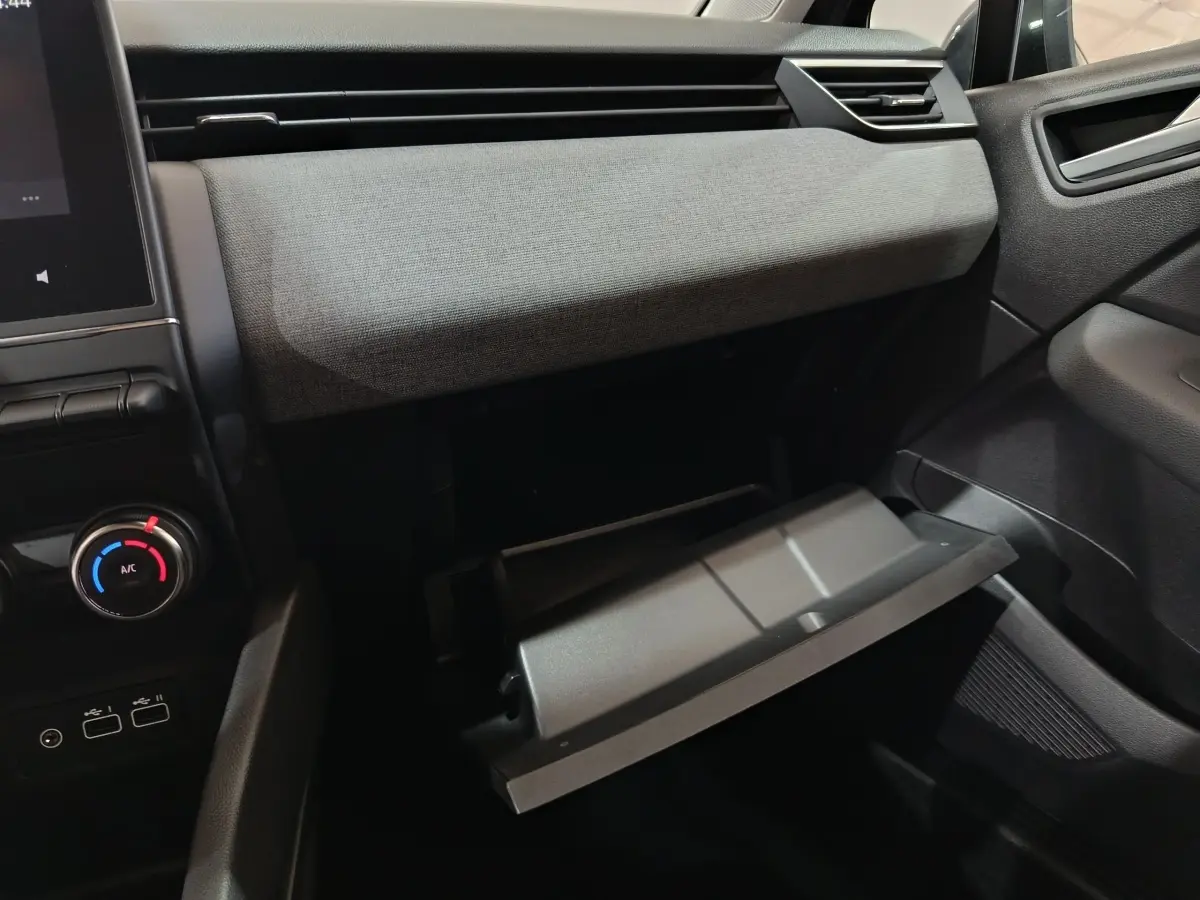 Vue intérieure côté passager de la Renault Clio 2025 gris clair, avec boîte à gants ouverte et tableau de bord textile.