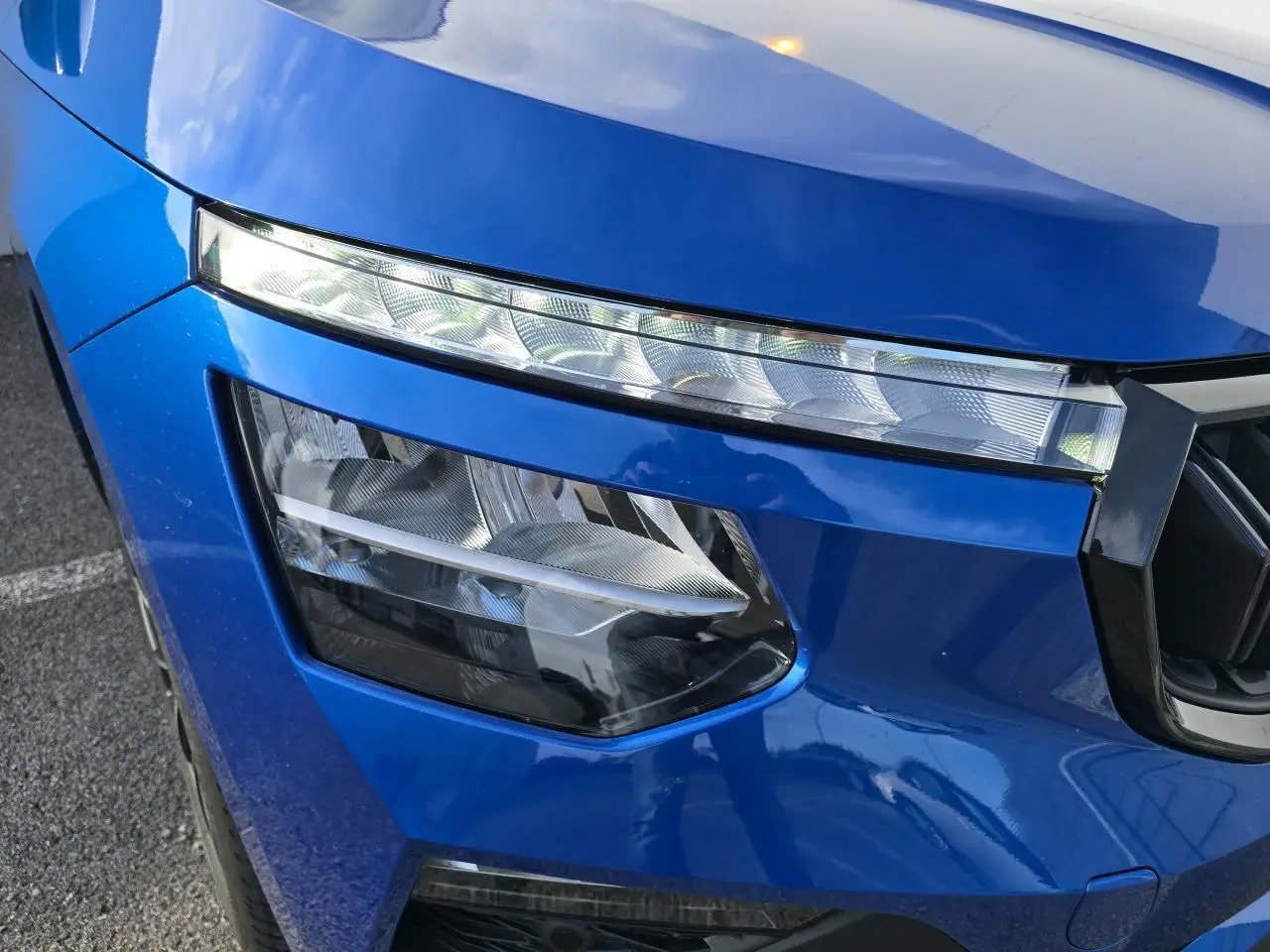 Gros plan sur le phare avant gauche du Skoda Kamiq 2025 bleu racing avec toit noir, mettant en valeur ses feux LED distinctifs.