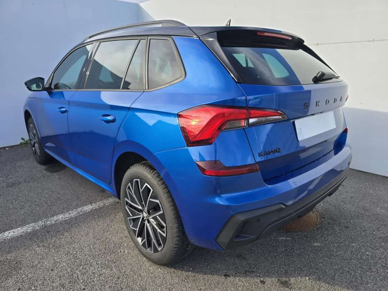 Vue 3/4 arrière droite d'un Skoda Kamiq bleu racing avec toit noir et jantes alliage 17 pouces.