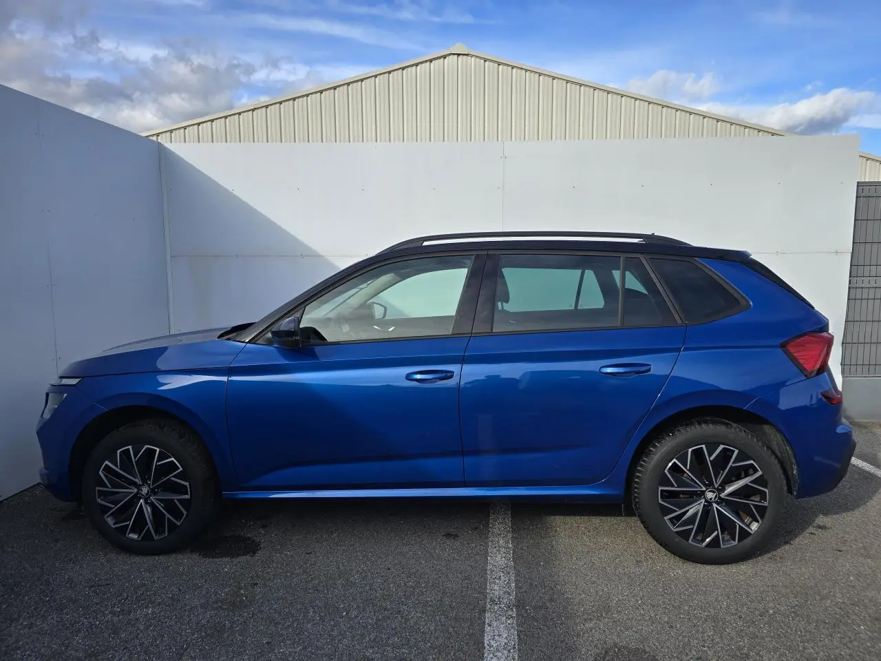 Vue de profil côté gauche d'un Skoda Kamiq bleu racing avec toit noir et jantes alliage 17 pouces.