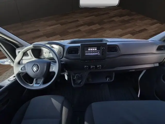 Vue intérieure frontale du tableau de bord et volant noir du Renault Master blanc, avec écran tactile central et commandes manuelles.