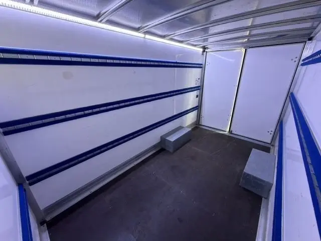 Vue intérieure arrière du Renault Master blanc 2023, montrant la caisse vide avec rails bleus et deux cales métalliques au sol.