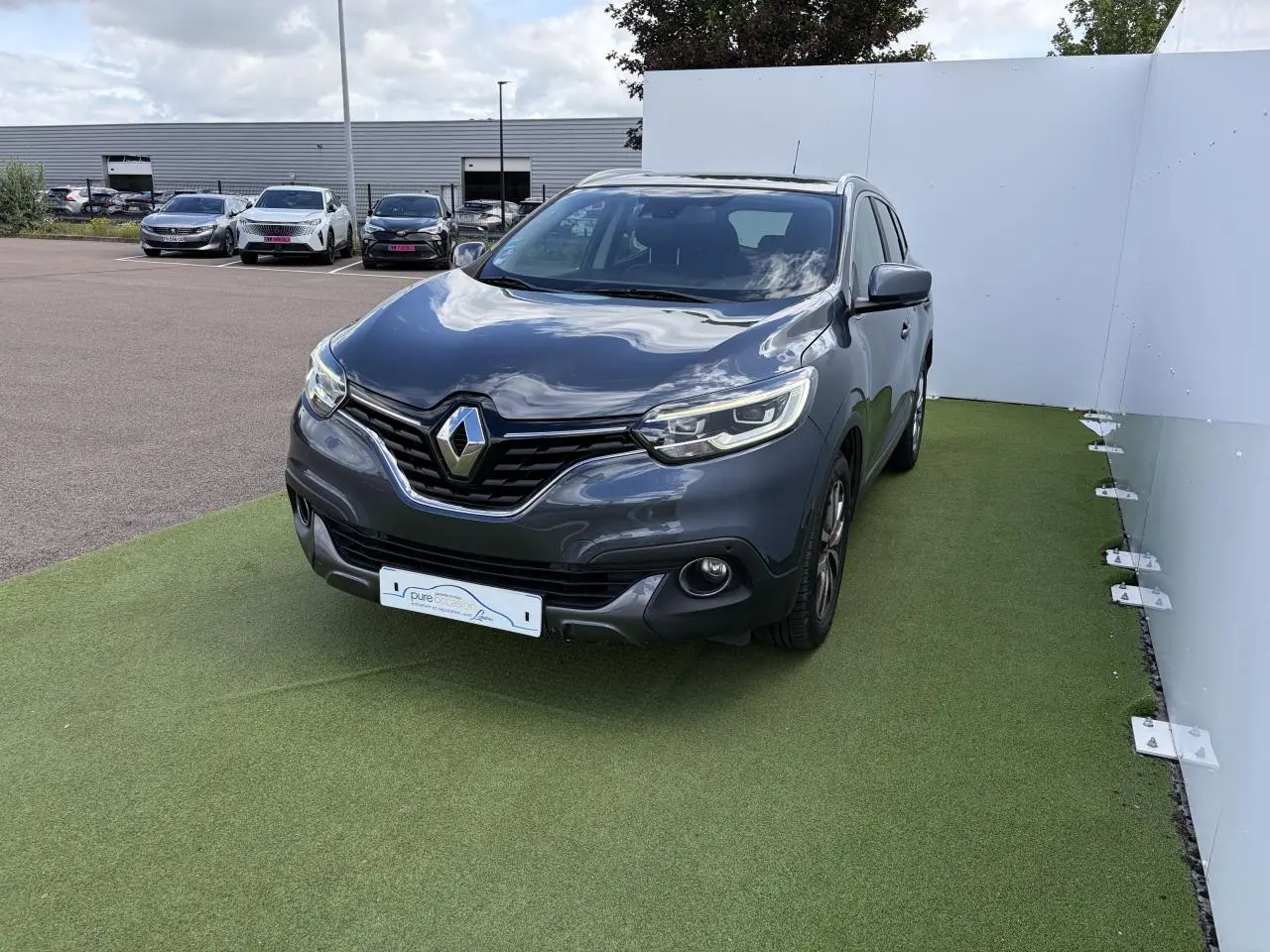 Renault Kadjar bleu métal en 3/4 avant droit, avec projecteurs LED et calandre chromée visible.