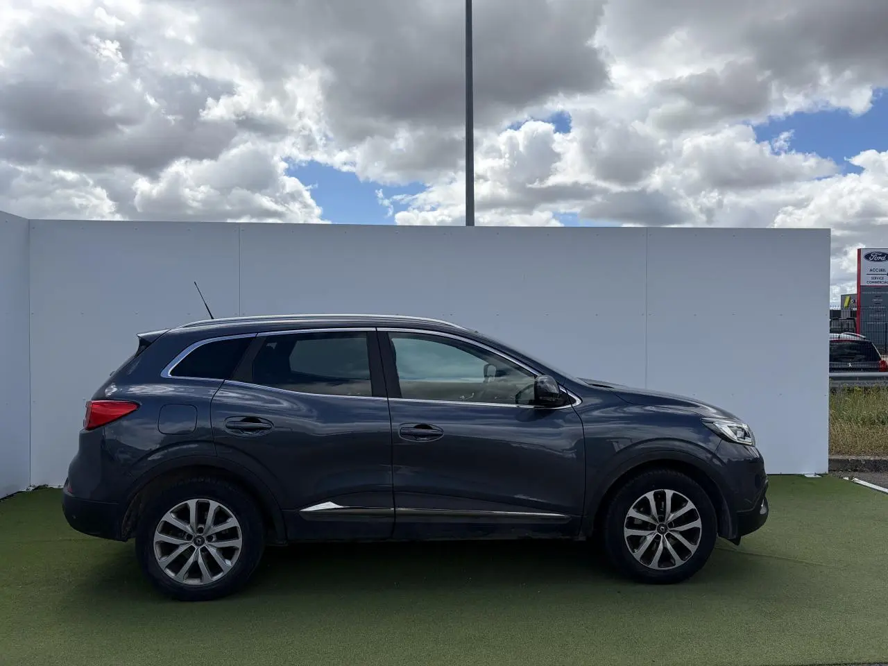 Profil droit du Renault Kadjar bleu métal 2016 avec jantes alliage 17 pouces et vitres surteintées.