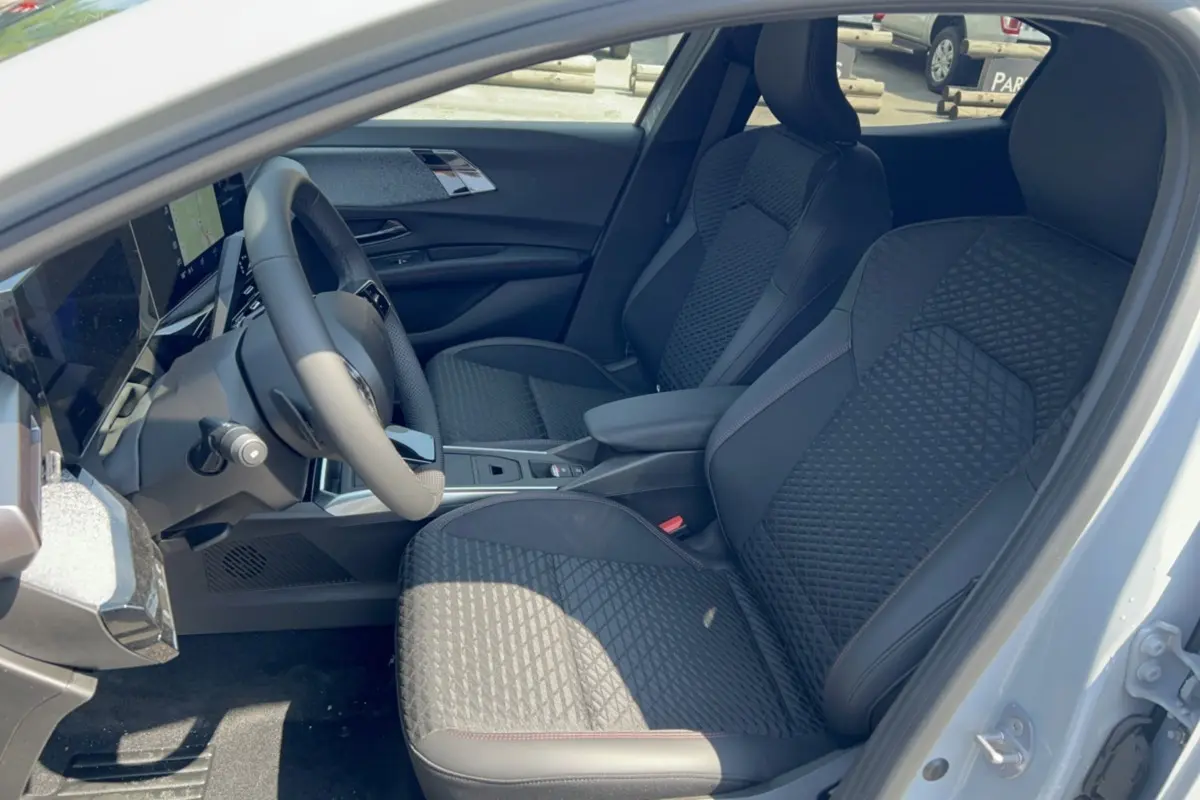 Vue intérieure côté conducteur de la Renault Clio 6 TCE 115 EDC Techno Plus avec sièges noirs texturés et volant multifonctions.