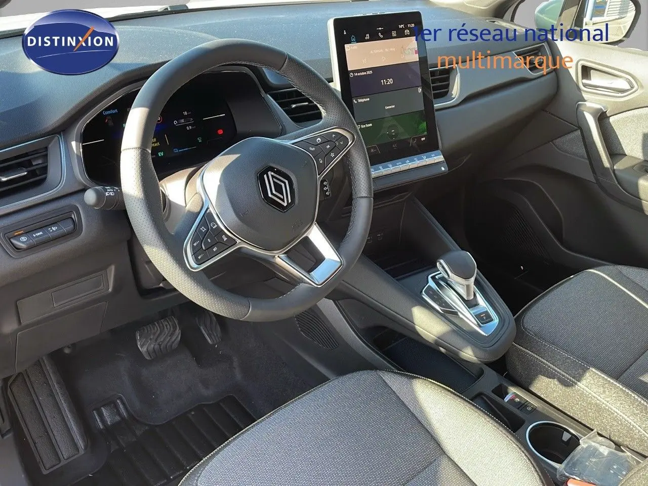Vue intérieure du poste de conduite du Renault Captur E-Tech hybride 2025, volant multifonction et écran tactile vertical.