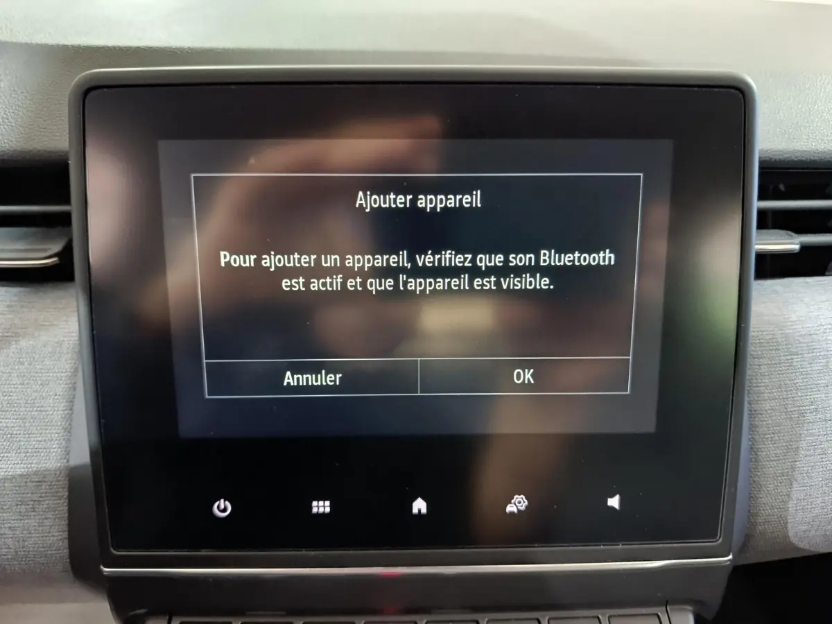 Écran tactile central affichant un message Bluetooth dans l'habitacle d'une Renault Clio gris clair, vue de face.