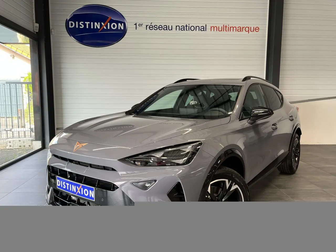 Vue 3/4 avant droite du CUPRA Formentor gris clair 2025 avec jantes alliage et logo CUPRA cuivré sur le capot.