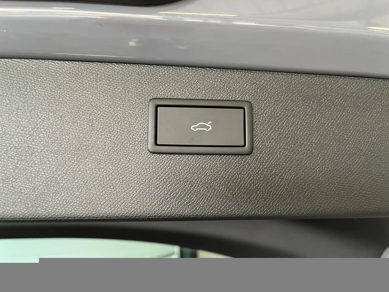 Bouton d'ouverture électrique du hayon sur la garniture intérieure noire du coffre du CUPRA Formentor gris clair.