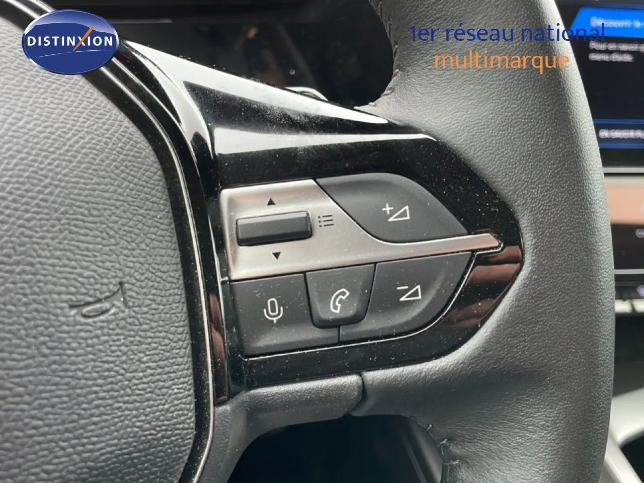 Gros plan sur les commandes multifonctions à gauche du volant cuir noir du Peugeot 408 gris selenium 2025.
