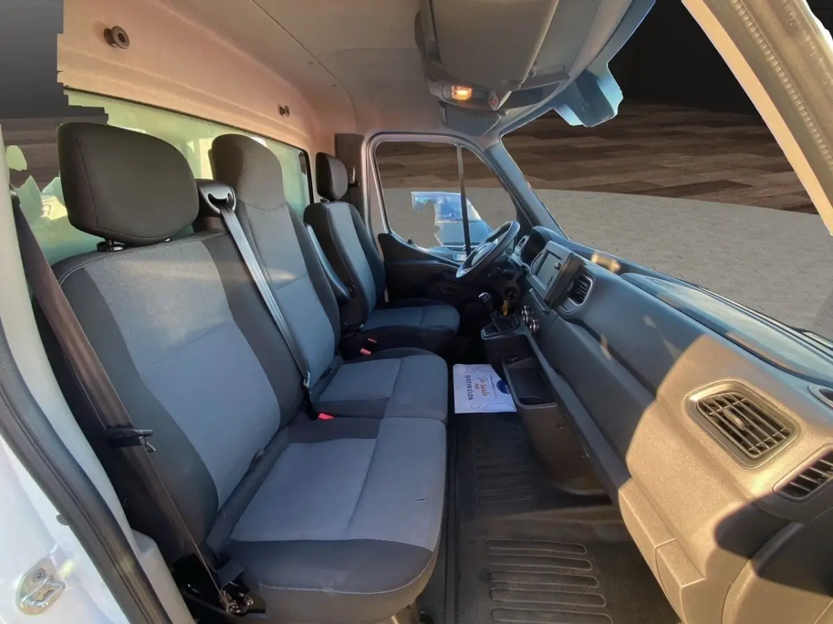 Vue intérieure côté conducteur du Renault Master blanc, montrant les sièges avant et le tableau de bord fonctionnel.