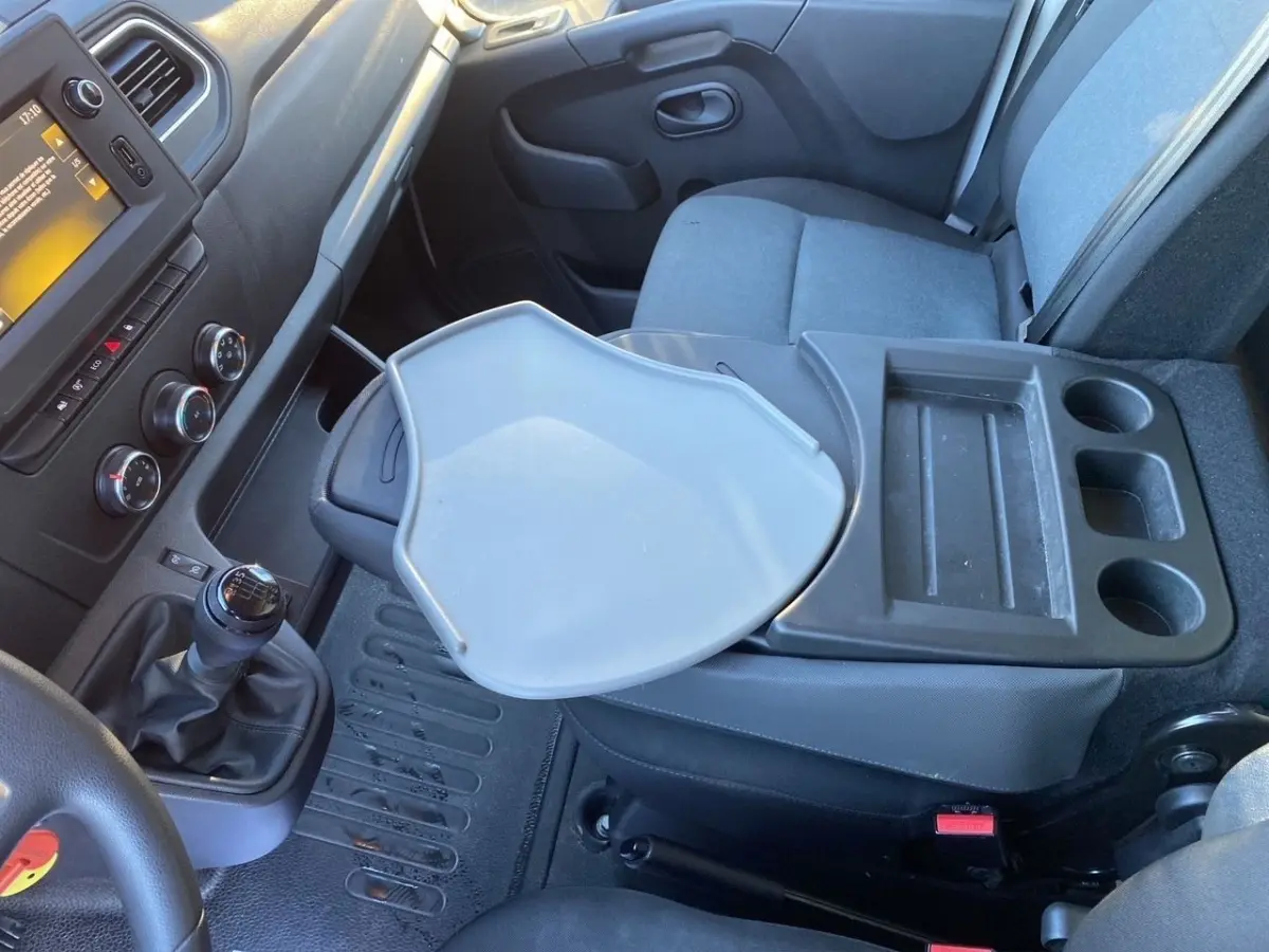 Vue intérieure côté passager du Renault Master 2023, montrant la console centrale avec tablette rabattable et sièges gris.