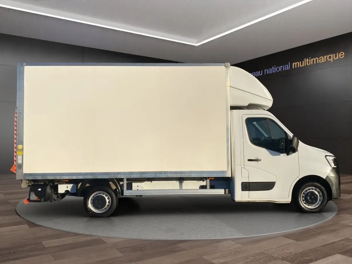 Vue latérale droite du Renault Master blanc avec caisse fermée et hayon, en intérieur showroom.