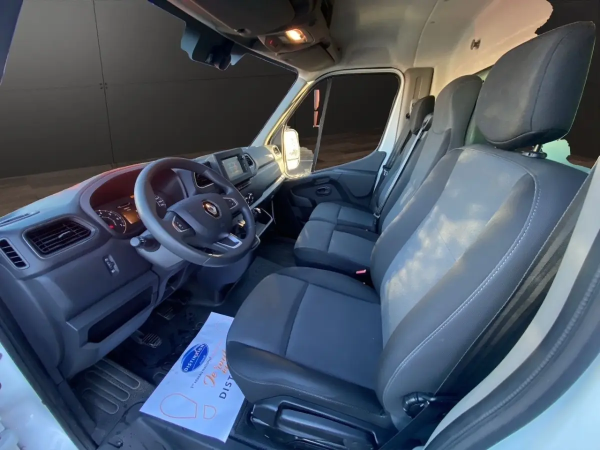 Vue intérieure côté conducteur du Renault Master blanc 2023, montrant le tableau de bord et les sièges avant gris foncé.