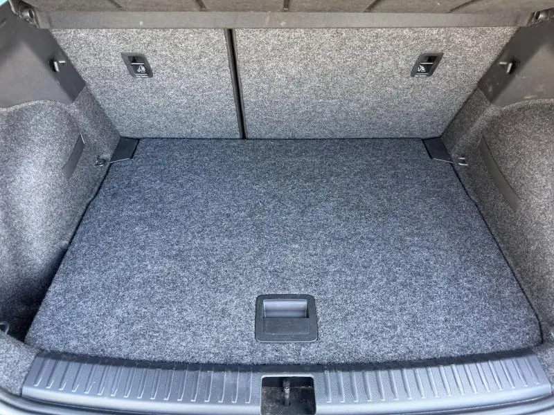 Coffre vu de l'intérieur d'un SEAT Arona 2025, revêtement gris et banquette arrière rabattable visible.