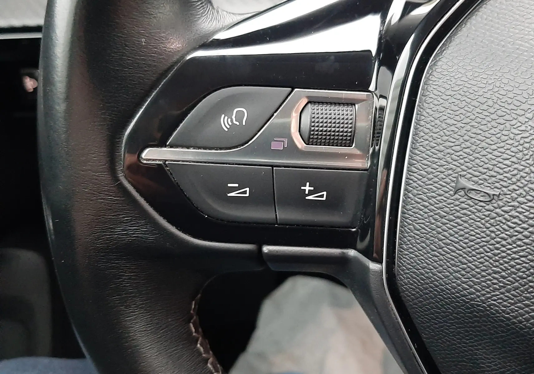Gros plan sur les commandes de volume et téléphone au volant noir d'une Peugeot 508 blanche, version 1.5 BlueHDi 130 Active.