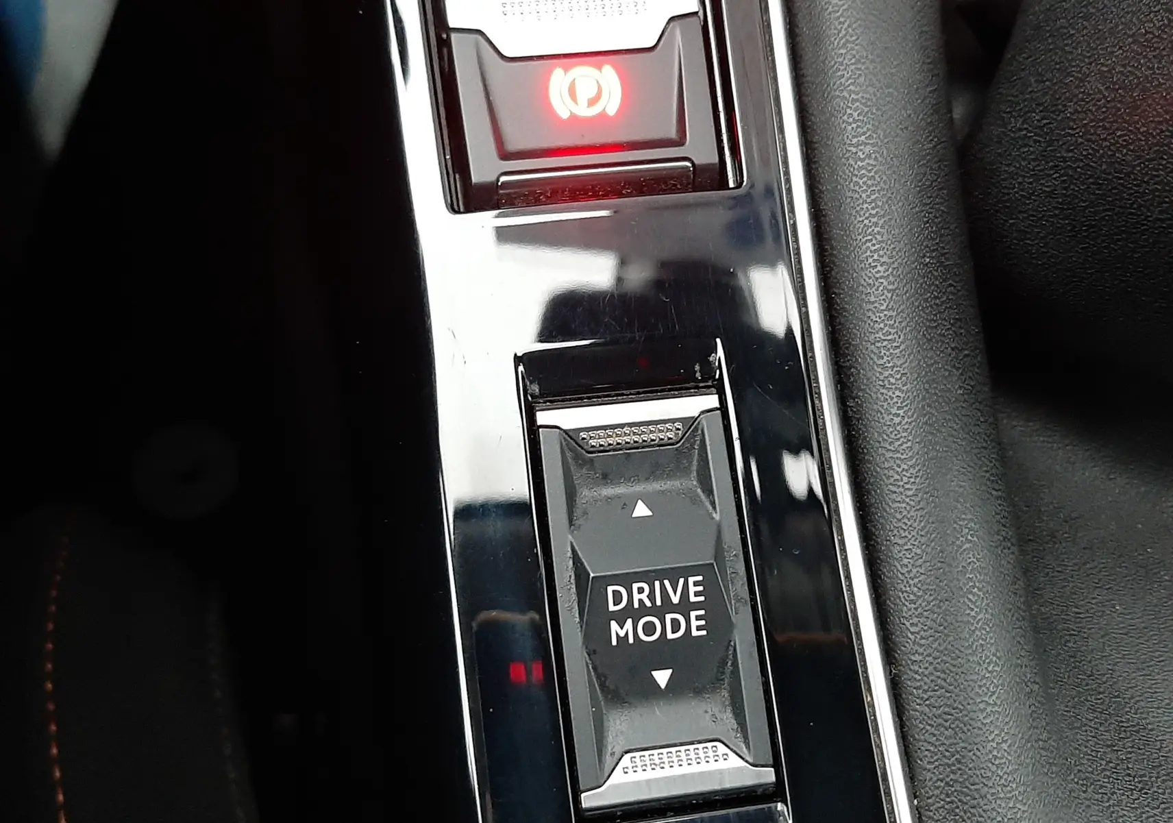Gros plan sur la console centrale noire de la Peugeot 508 blanche, montrant le bouton Drive Mode et le frein à main électronique.