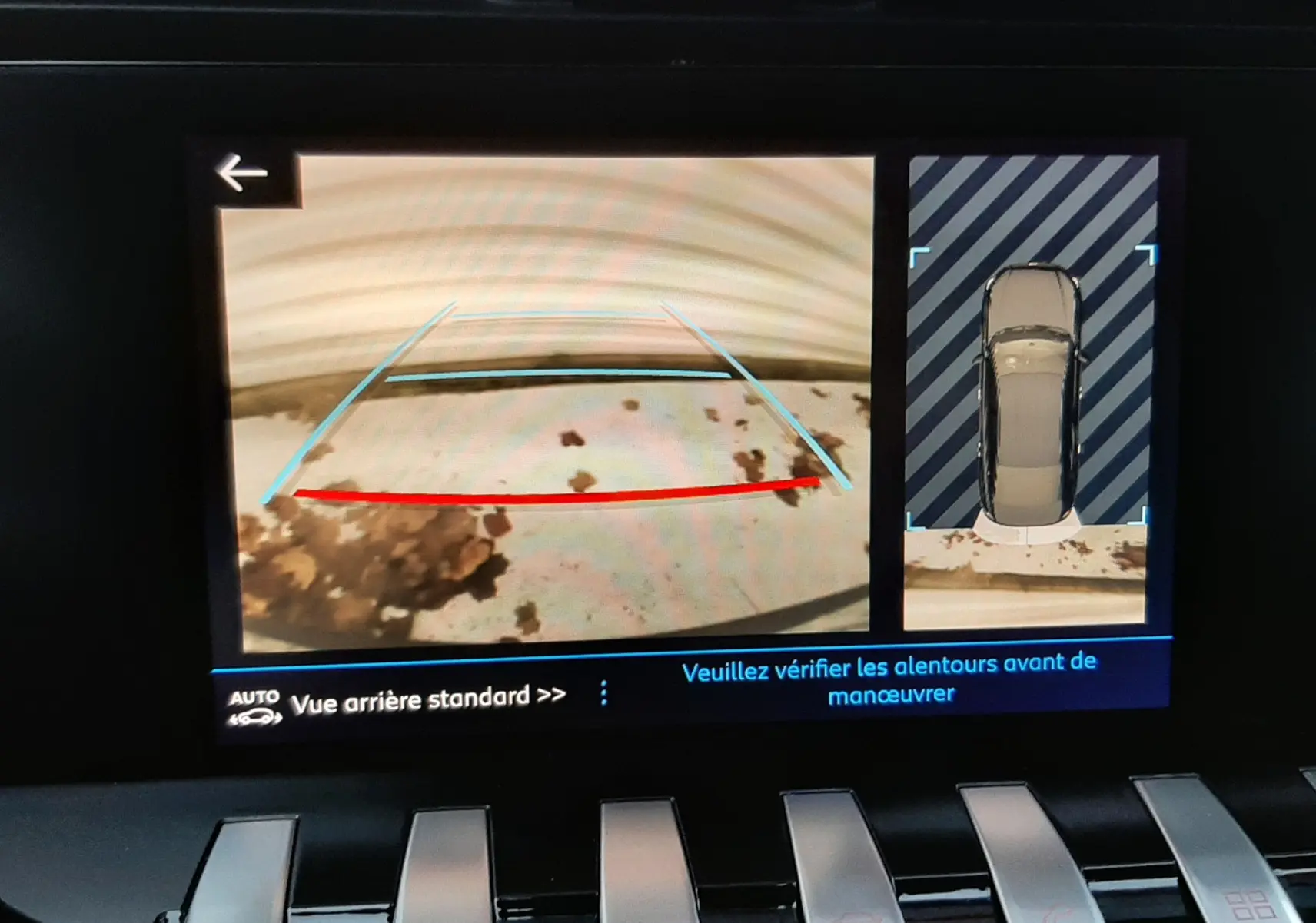 Vue de l'écran de caméra de recul de la Peugeot 508 blanche, affichant l'arrière et la vue 360° du véhicule en stationnement.