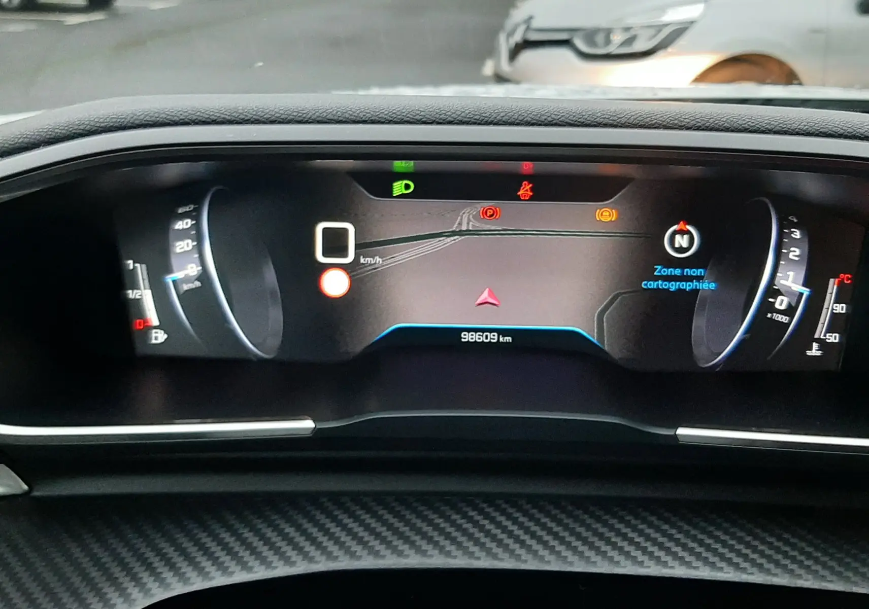 Vue rapprochée du tableau de bord numérique du Peugeot 508 blanc, affichant 98609 km et alertes actives.