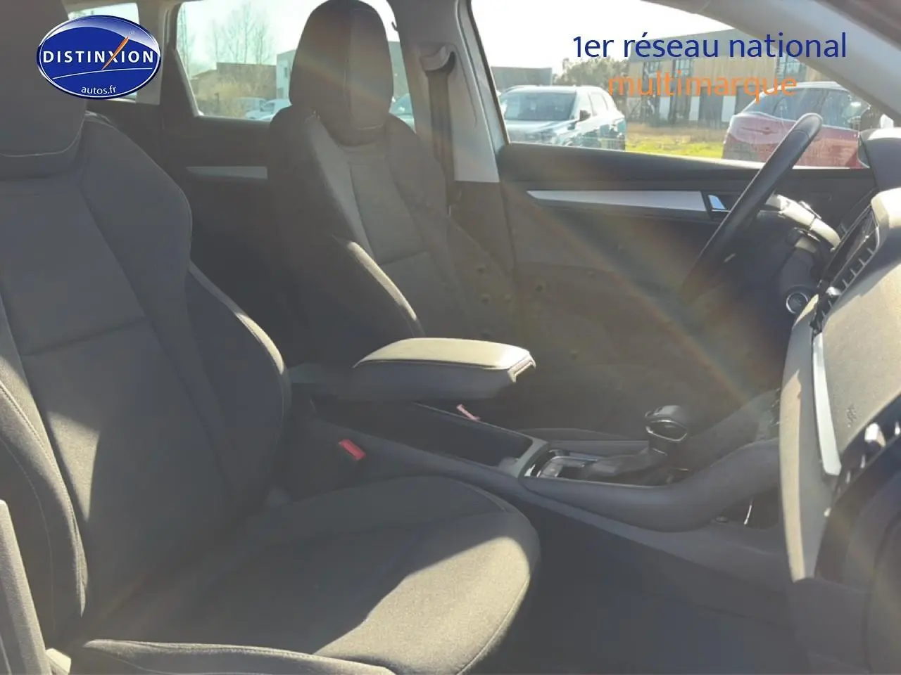 Vue intérieure côté droit du Skoda Karoq gris 2025, montrant les sièges avant et la console centrale avec accoudoir.