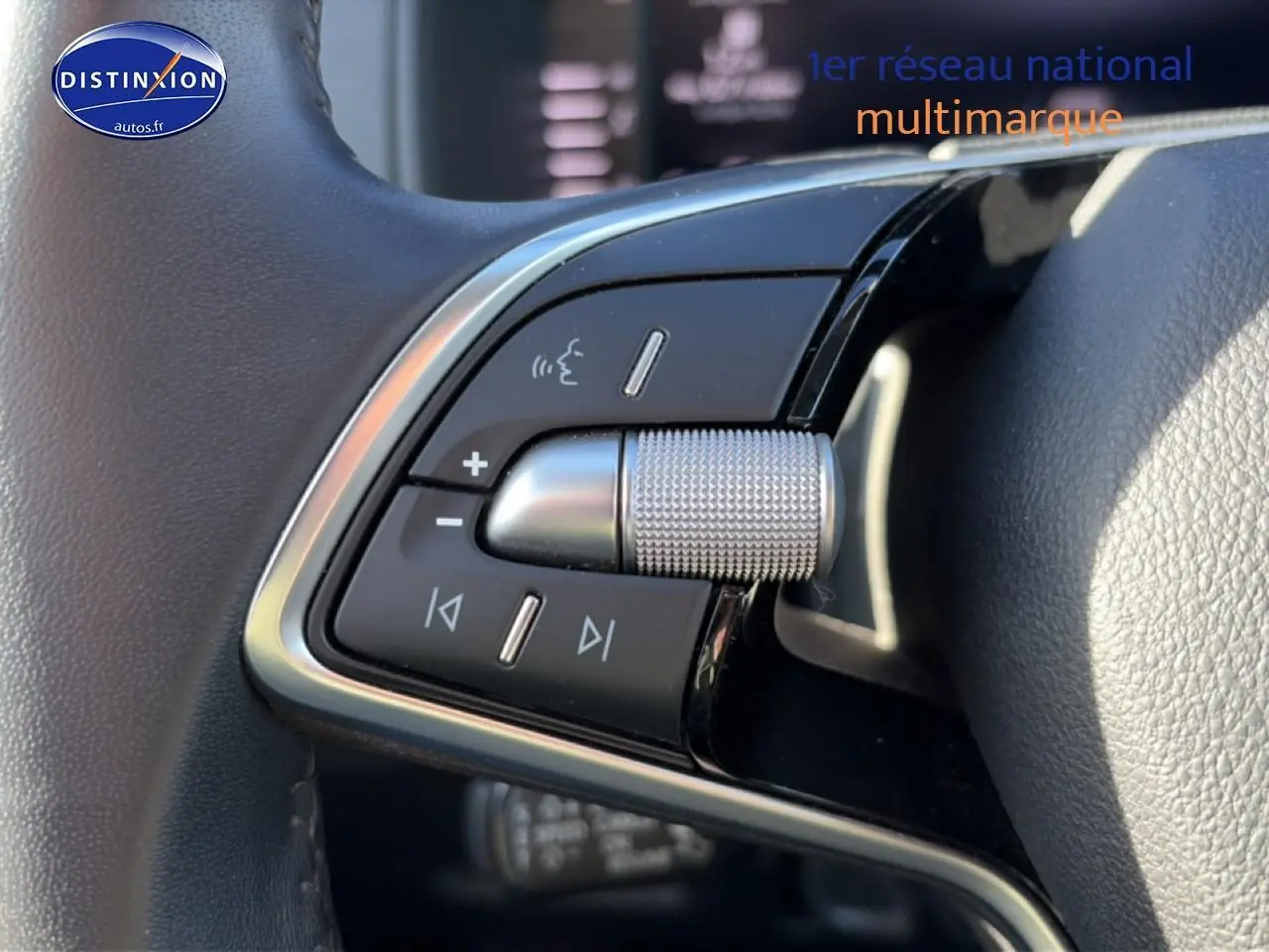 Gros plan sur les commandes audio et vocales au volant cuir noir du Skoda Karoq gris 2025.