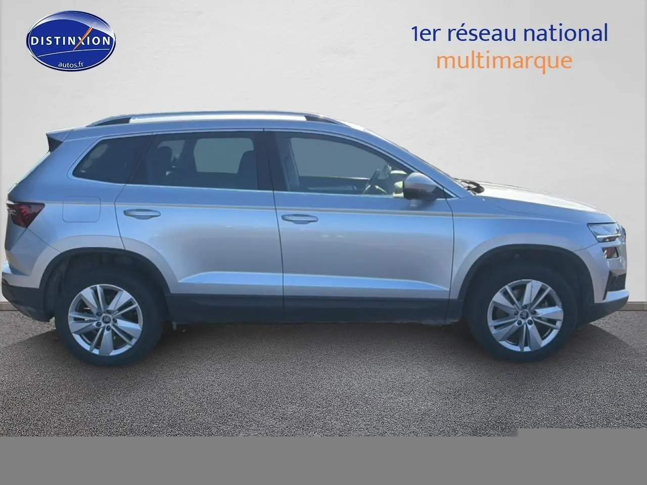 Vue latérale droite d'un Skoda Karoq gris 2025 avec barres de toit et jantes alliage.