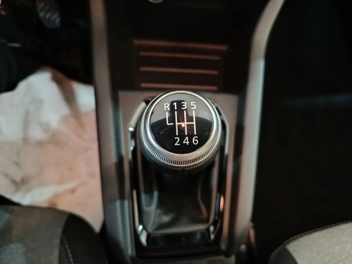 Gros plan sur le levier de vitesses manuel noir de la Renault Clio Evolution Blue dCi 100, intérieur sombre.