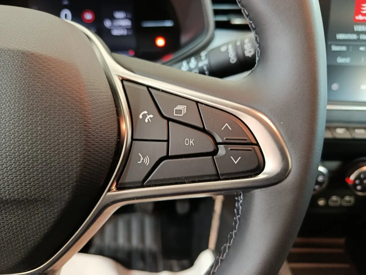 Gros plan sur les commandes multifonctions à droite du volant cuir noir de la Renault Clio Evolution Blue dCi 100 2025.