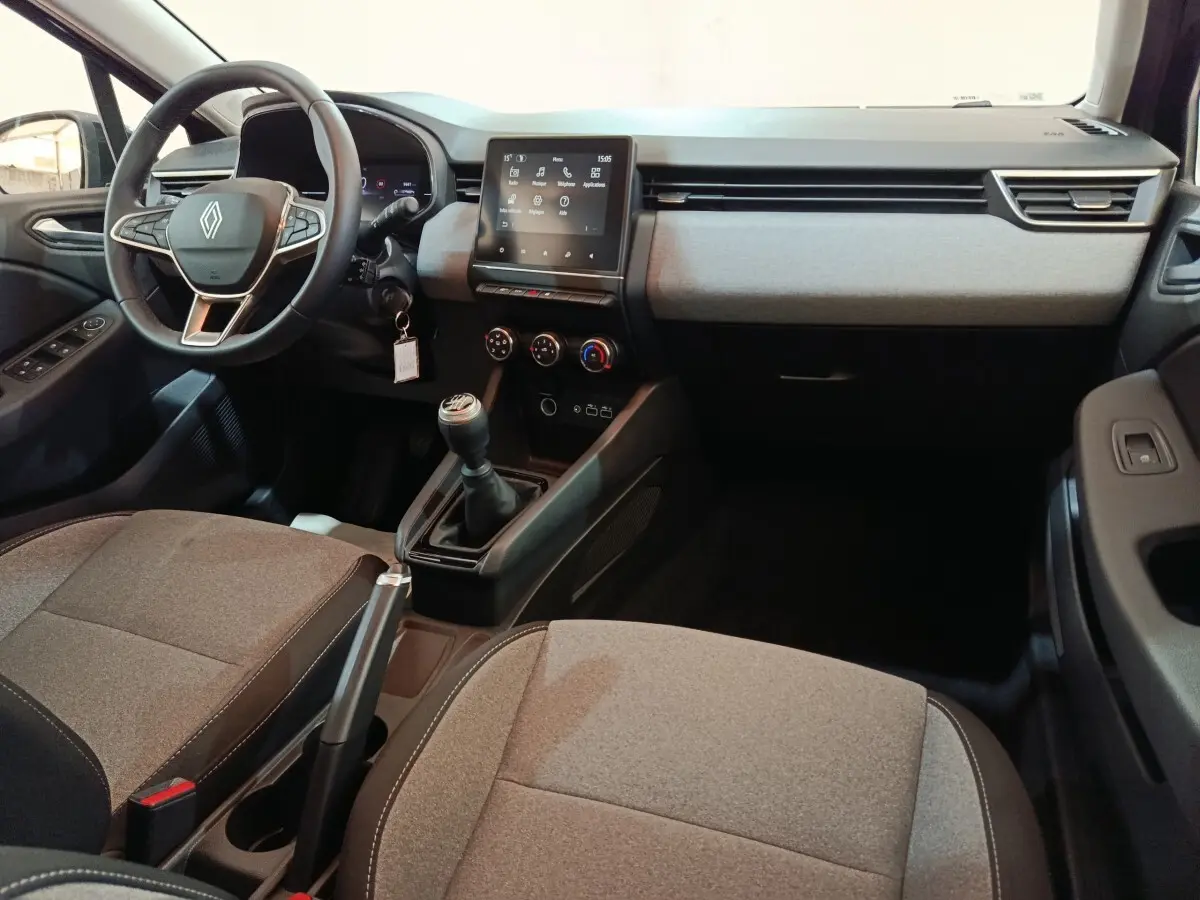 Vue intérieure avant de la Renault Clio Evolution Blue dCi 100 2025, tableau de bord gris clair avec écran tactile central et volant multifonctions.