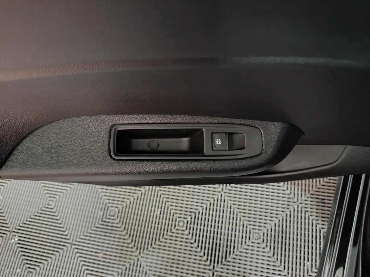 Détail de la commande de verrouillage des portes sur la portière intérieure noire d’une Renault Clio Evolution Blue dCi 100.