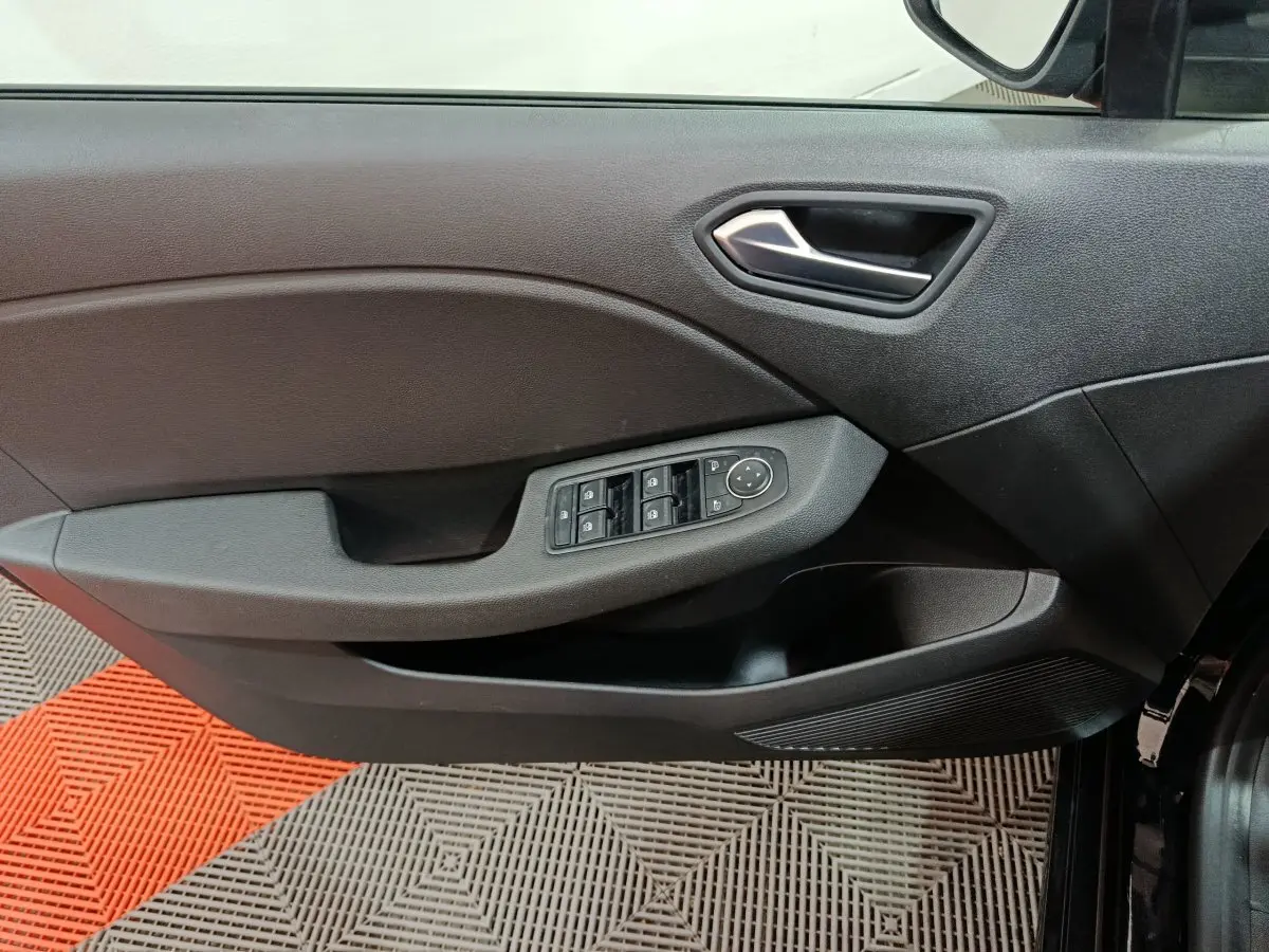 Vue intérieure du panneau de porte avant gauche de la Renault Clio noire, avec commandes électriques des vitres et rétroviseurs.
