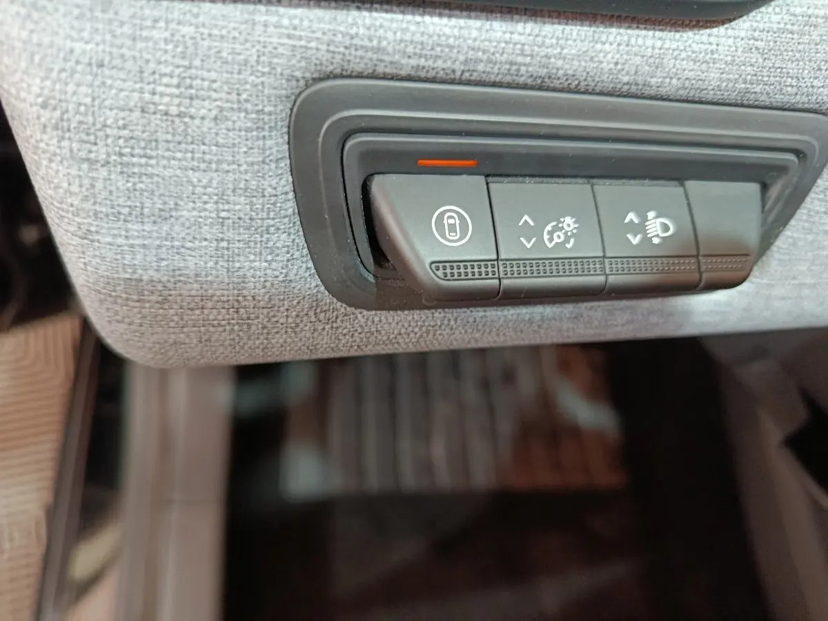 Gros plan sur les commandes de réglage des phares et verrouillage, intégrées dans le tableau de bord gris clair d’une Renault Clio noire.