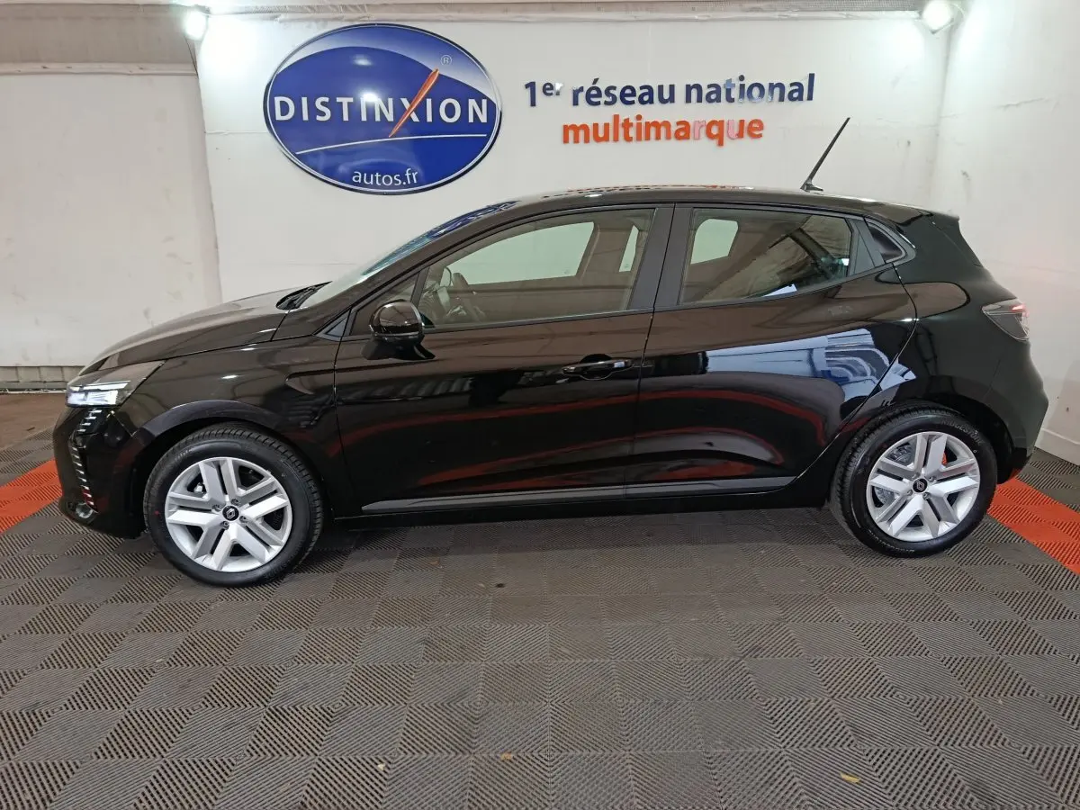 Profil côté gauche d'une Renault Clio noire 2025 garée en intérieur avec jantes alliage et feux LED visibles.