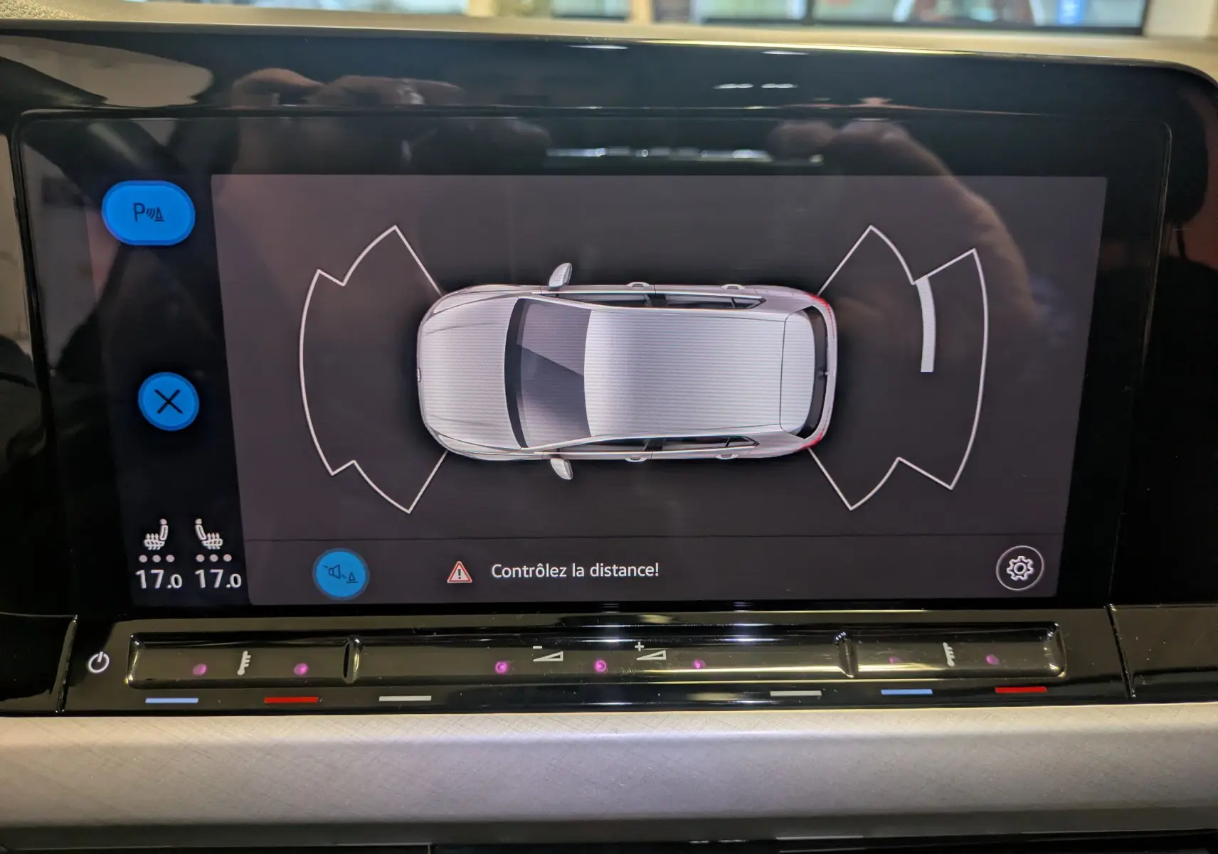 Vue du tableau de bord de la Volkswagen Golf 1.5 eTSI 2024, écran affichant l'aide au stationnement en vue aérienne.