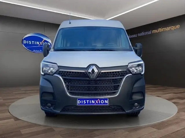 Vue avant d’un Renault Master blanc avec calandre noire et logo Renault bien visible, sur fond intérieur showroom.