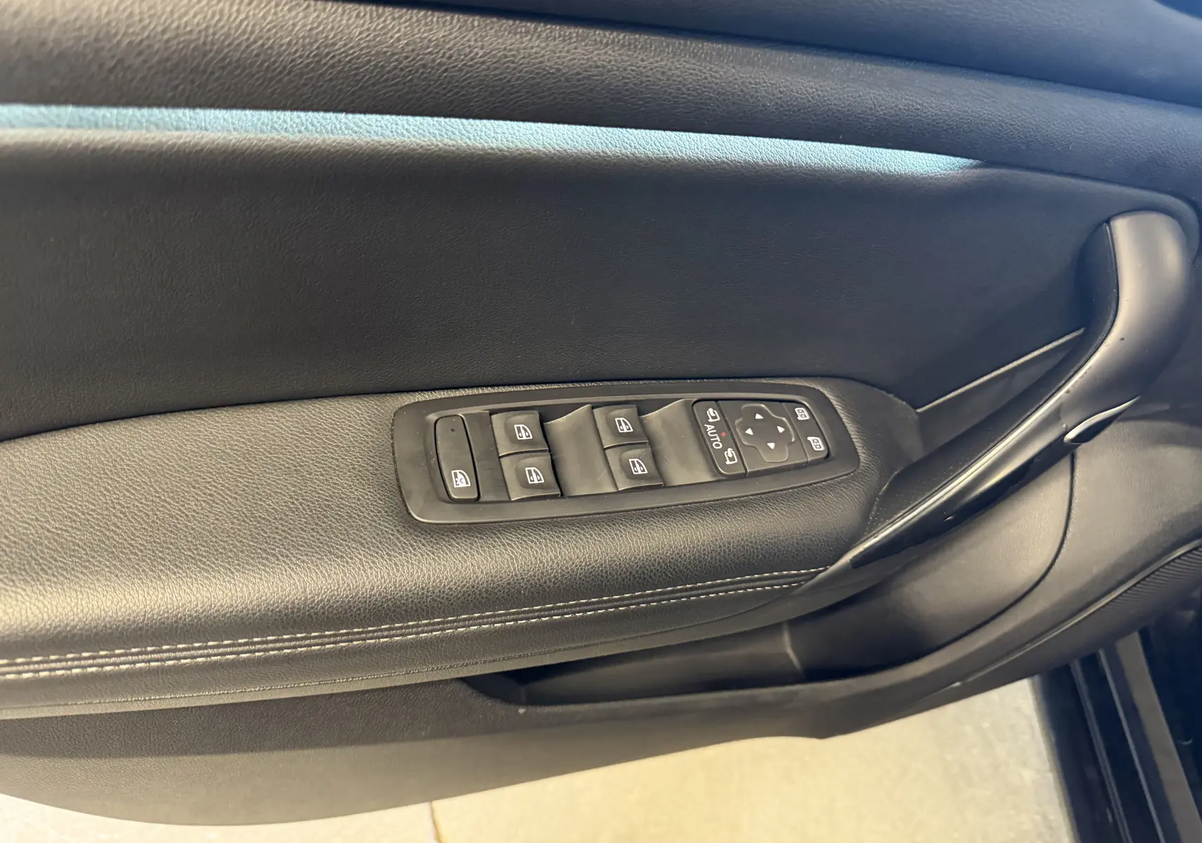 Gros plan sur la commande des vitres et rétroviseurs côté conducteur de la Renault Mégane Estate noire 2024.