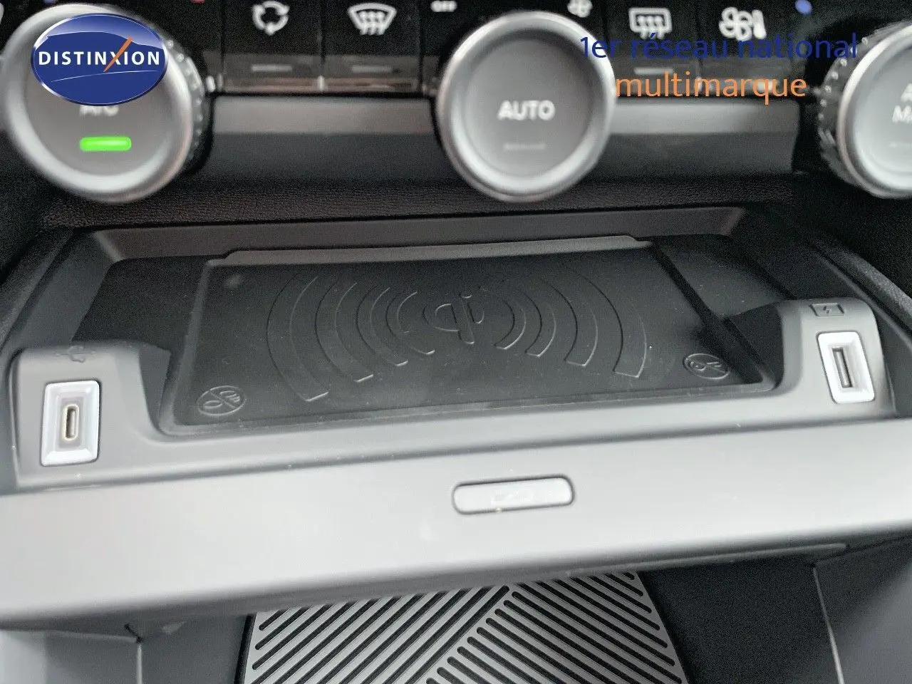 Gros plan sur la console centrale de la Citroën C4 2024 avec zone de recharge sans fil et commandes de climatisation.