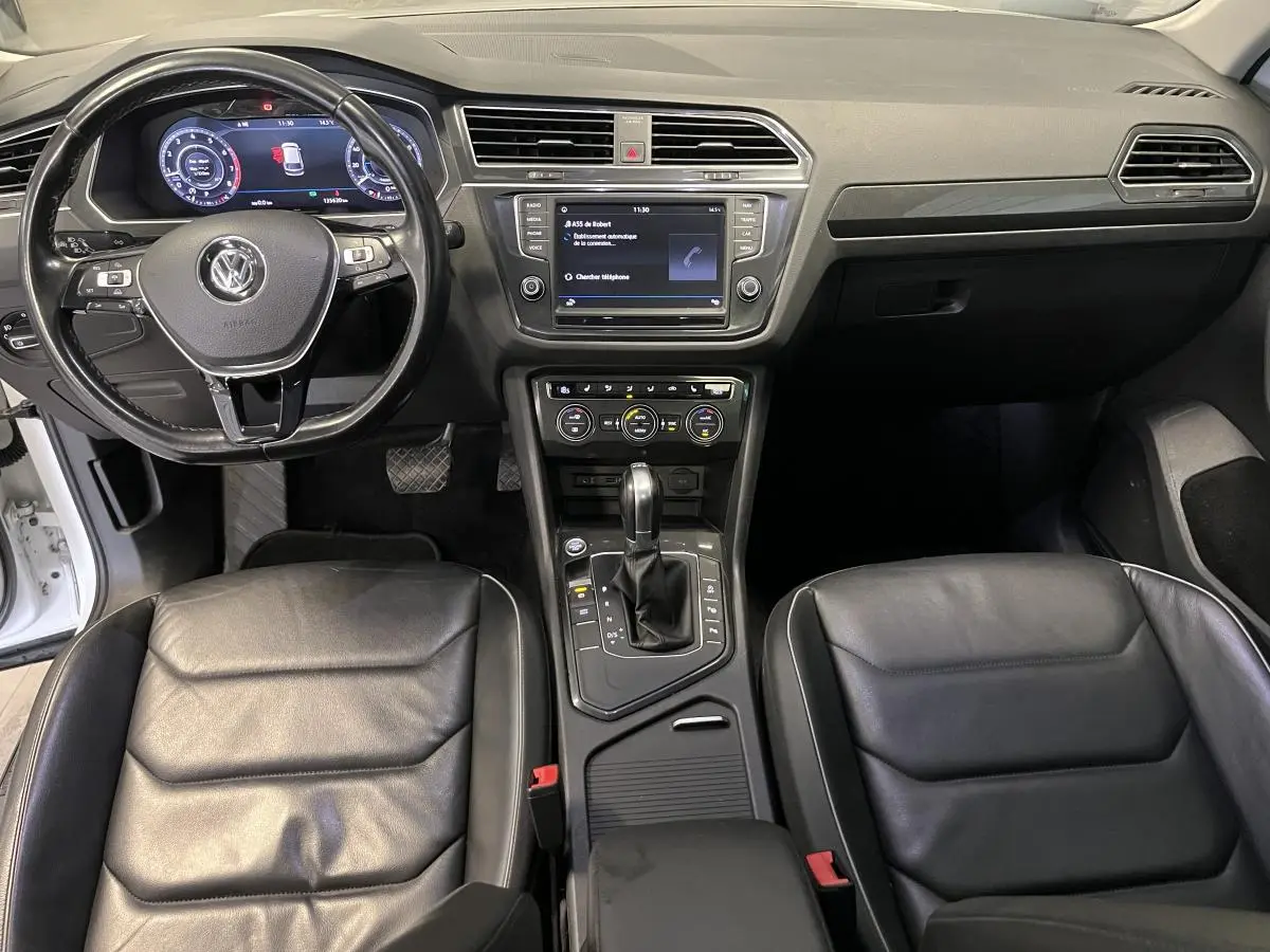 Vue intérieure frontale du Volkswagen Tiguan 2017 avec sièges cuir noirs, tableau de bord et console centrale équipée.