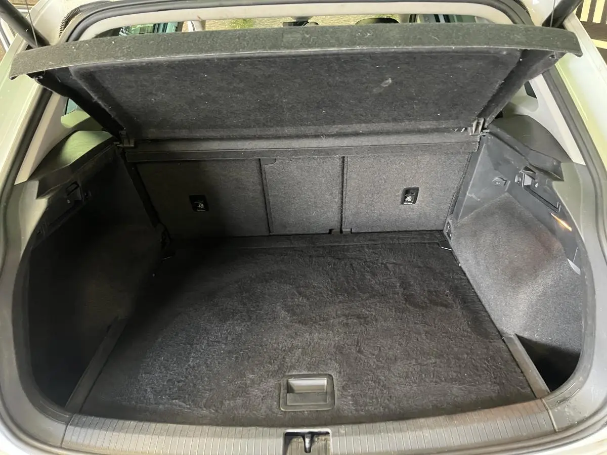 Coffre ouvert du Volkswagen Tiguan blanc vu de l'arrière, montrant un espace de chargement propre et vide.