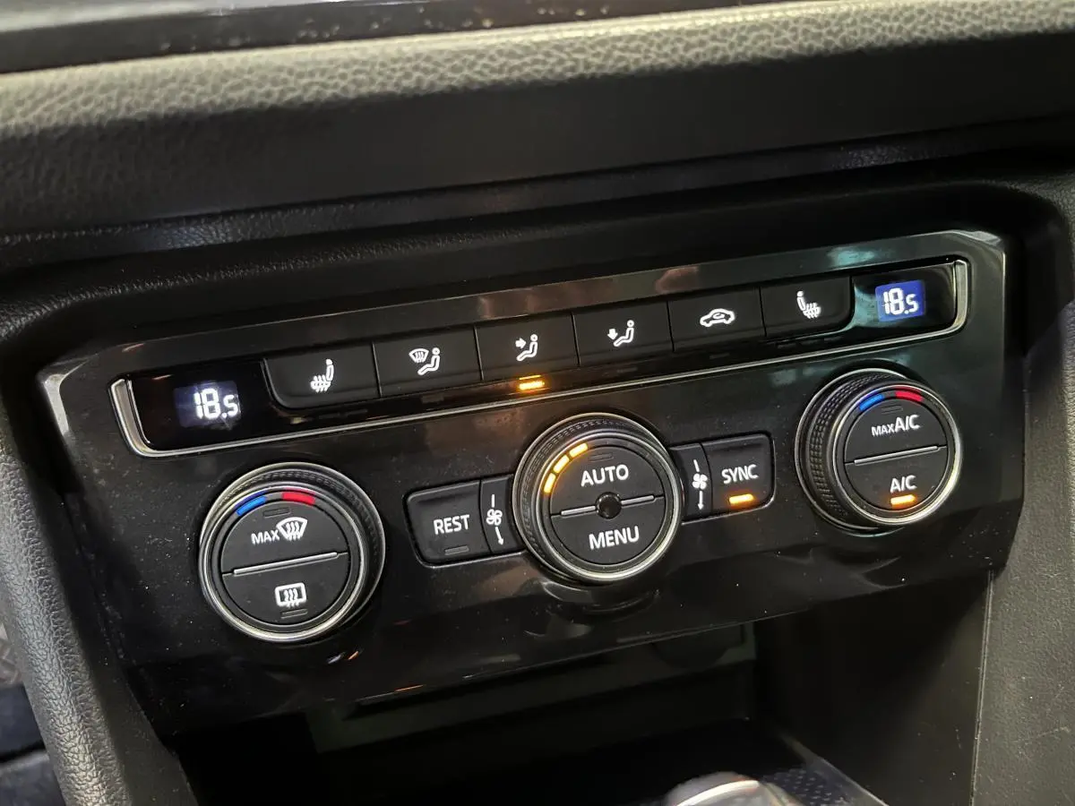 Gros plan sur la console de climatisation automatique du Volkswagen Tiguan blanc, avec réglages digitaux à 18,5°C.