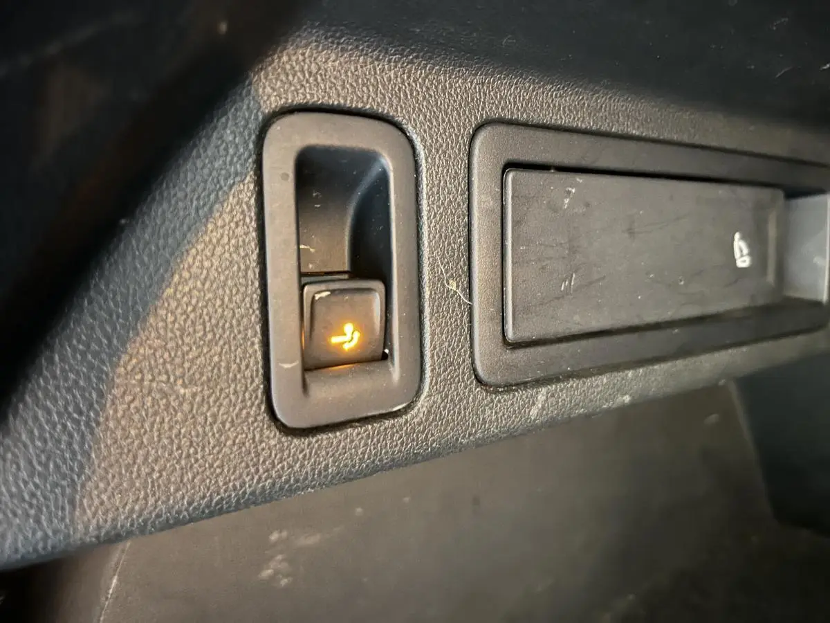 Gros plan sur le bouton de rabattement électrique du siège arrière dans l'habitacle du Volkswagen Tiguan blanc.