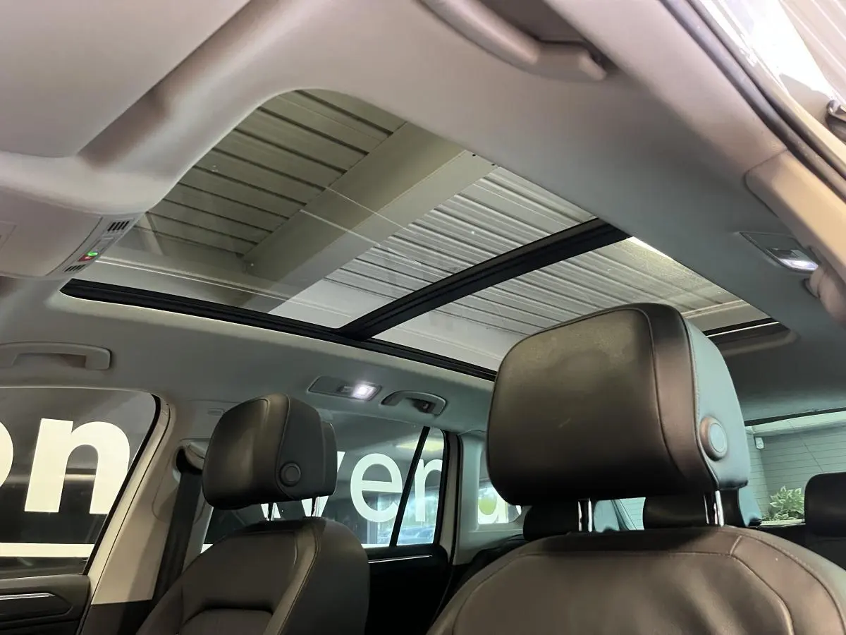 Intérieur du Volkswagen Tiguan 2017 vu des sièges avant, toit ouvrant panoramique et sièges cuir noirs visibles.