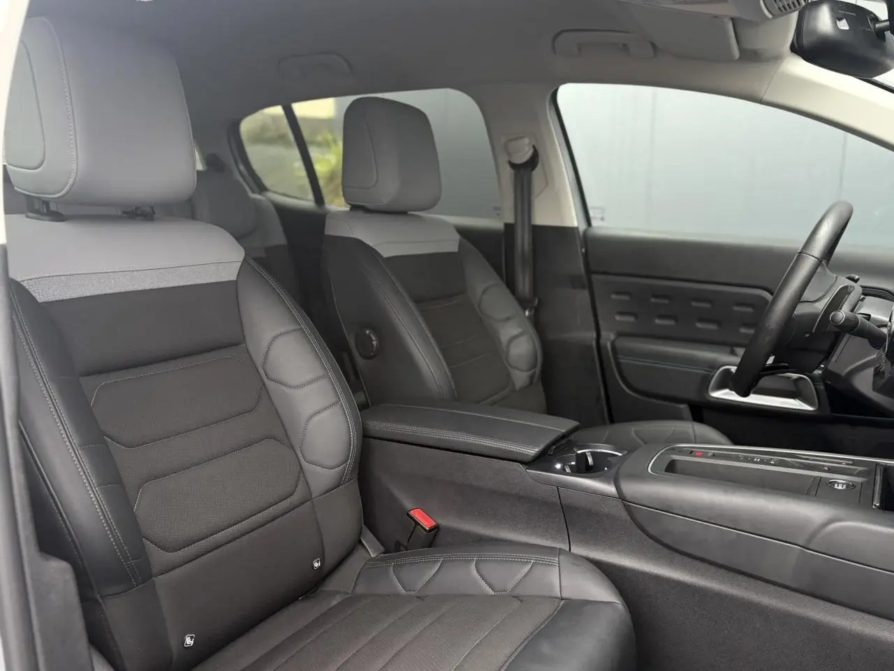 Vue intérieure côté conducteur du Citroën C5 Aircross Hybrid 2024, sièges Advanced Comfort noirs et gris, volant cuir.
